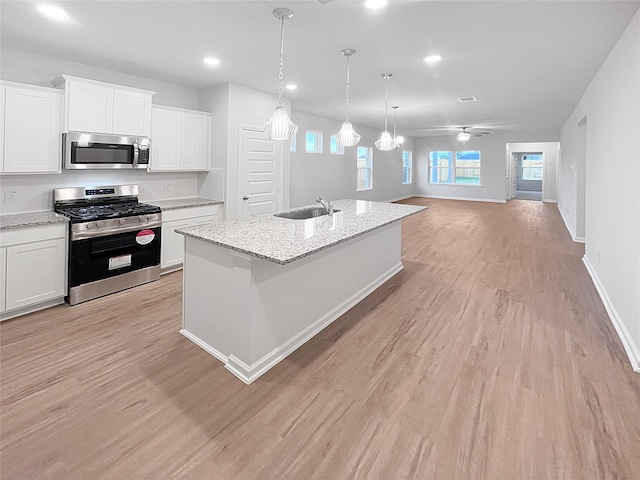 kitchen with white cabinetry, appliances with stainless steel finishes, sink, and a center island with sink