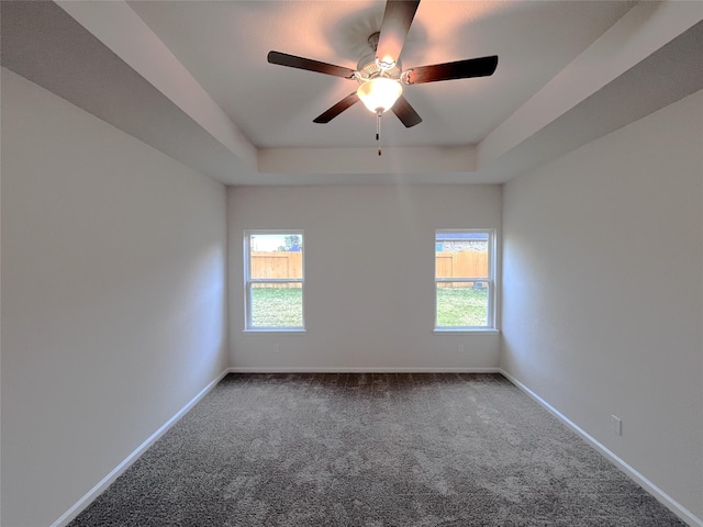 carpeted spare room with ceiling fan and a raised ceiling