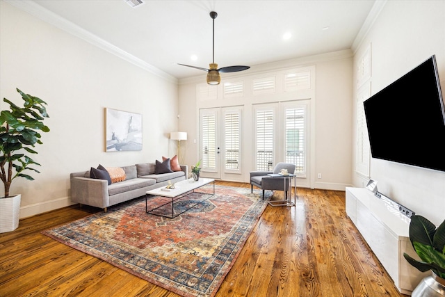 living room featuring baseboards, wood finished floors, a ceiling fan, and crown molding