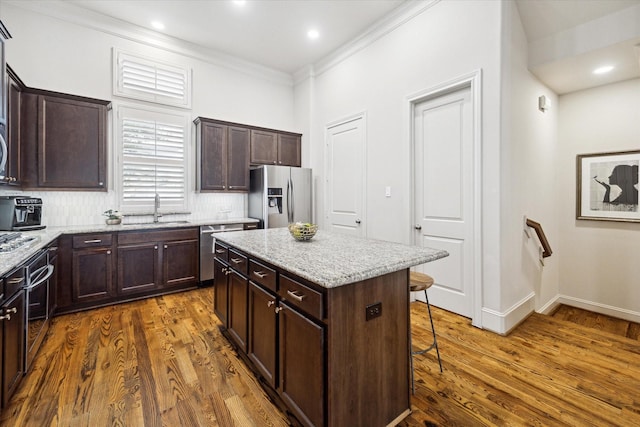 kitchen featuring dark wood-style floors, stainless steel appliances, a breakfast bar area, and a sink