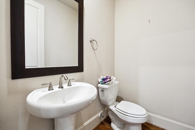 half bathroom with toilet, baseboards, and wood finished floors