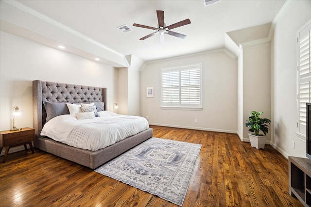 bedroom with ornamental molding, visible vents, baseboards, and wood finished floors