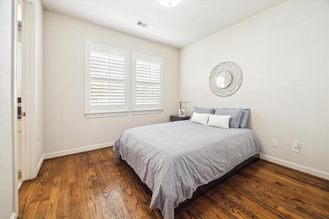 bedroom with visible vents, baseboards, and wood finished floors