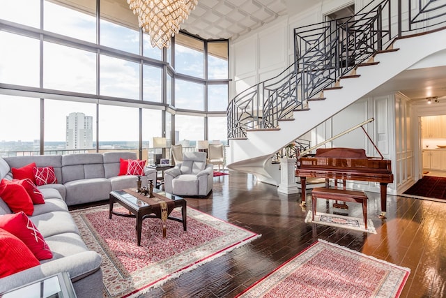 living room with a notable chandelier, a towering ceiling, floor to ceiling windows, and dark hardwood / wood-style floors