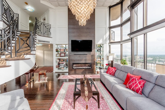 living room featuring hardwood / wood-style flooring, a wall of windows, an inviting chandelier, and a towering ceiling