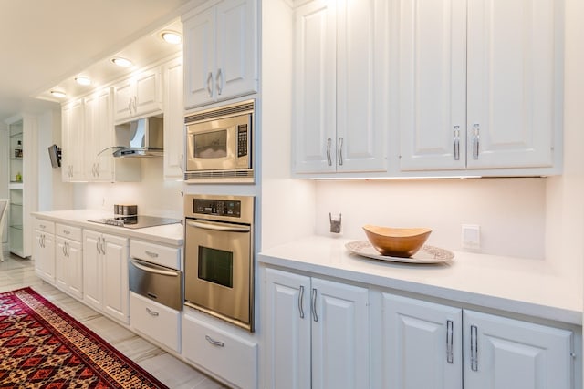 kitchen featuring stainless steel appliances, white cabinetry, and wall chimney range hood