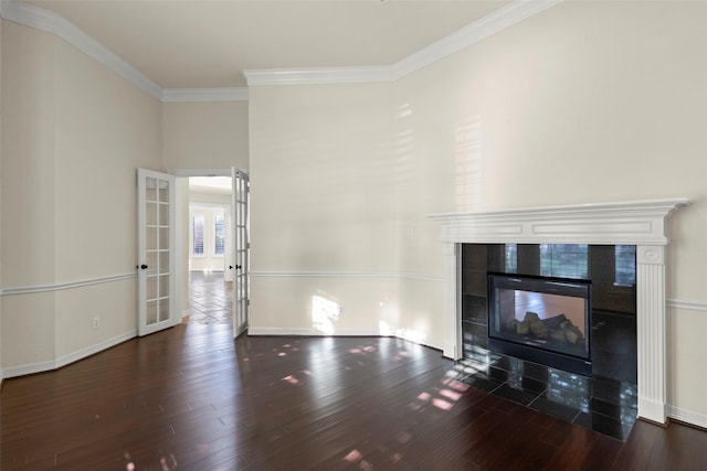 unfurnished living room featuring dark wood-type flooring, ornamental molding, a tiled fireplace, and french doors