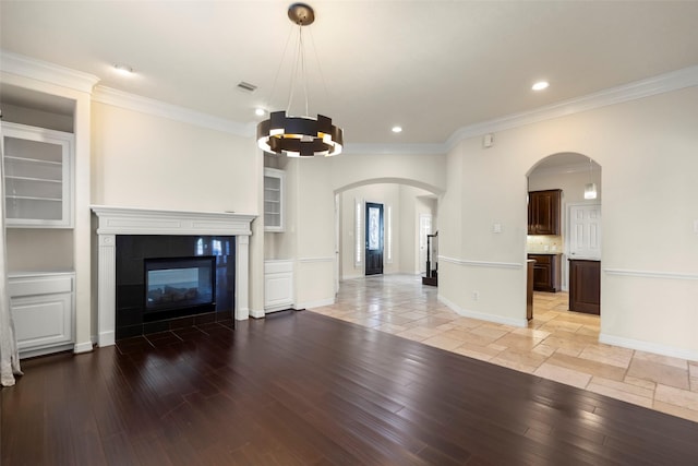 unfurnished living room with ornamental molding, a fireplace, a chandelier, and light wood-type flooring