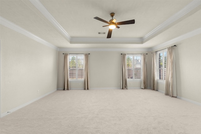 spare room with a tray ceiling, ornamental molding, light colored carpet, and ceiling fan