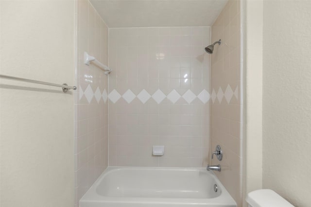 bathroom with toilet and tiled shower / bath combo