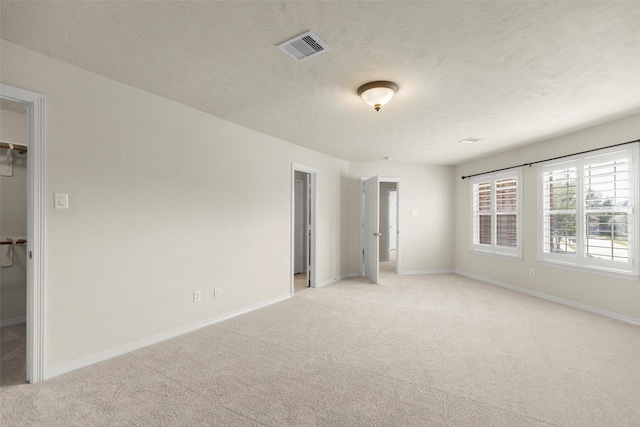 unfurnished room with light colored carpet and a textured ceiling