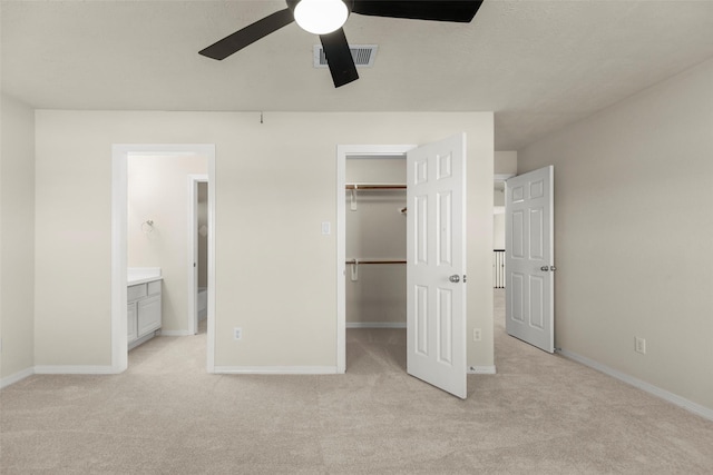 unfurnished bedroom featuring a closet, connected bathroom, a spacious closet, and light carpet