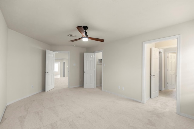 unfurnished bedroom featuring ceiling fan, light colored carpet, and a walk in closet