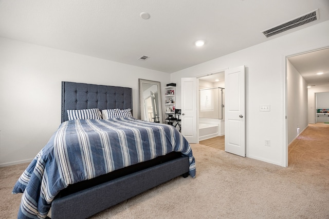 bedroom with ensuite bathroom and carpet flooring