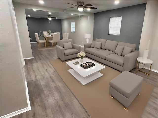 living area featuring ceiling fan, baseboards, and wood finished floors