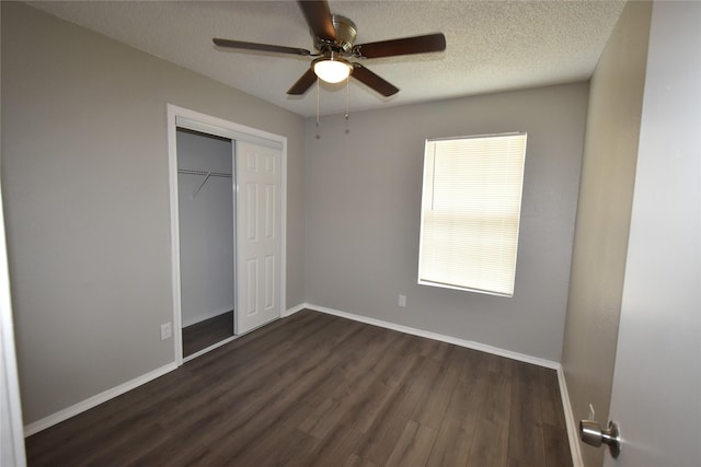 unfurnished bedroom featuring dark wood-type flooring, a ceiling fan, a textured ceiling, a closet, and baseboards