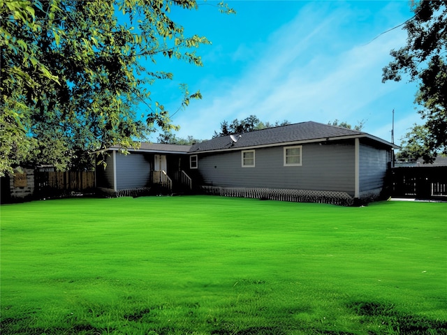 rear view of property featuring a yard and fence