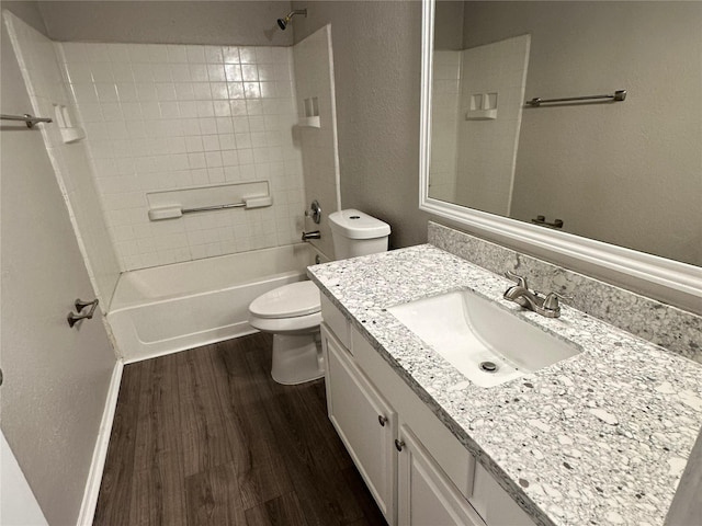 full bathroom featuring vanity, hardwood / wood-style floors, tiled shower / bath combo, and toilet