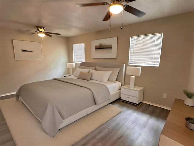 bedroom featuring ceiling fan, dark hardwood / wood-style floors, and multiple windows