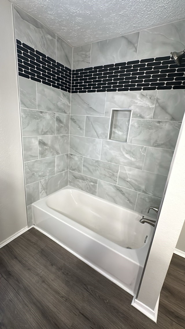 bathroom featuring baseboards, a textured ceiling, wood finished floors, and bathtub / shower combination