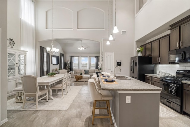 kitchen featuring visible vents, arched walkways, a sink, black appliances, and dark brown cabinetry