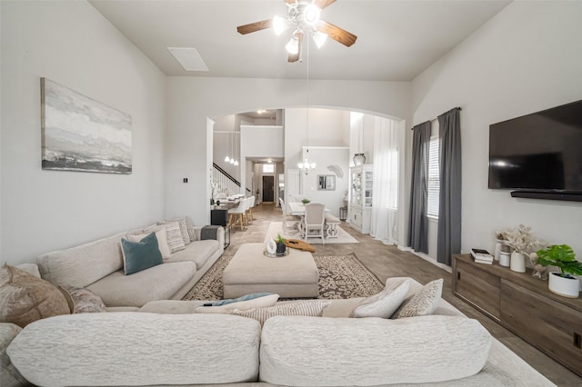 living room featuring stairs, vaulted ceiling, carpet flooring, and ceiling fan with notable chandelier