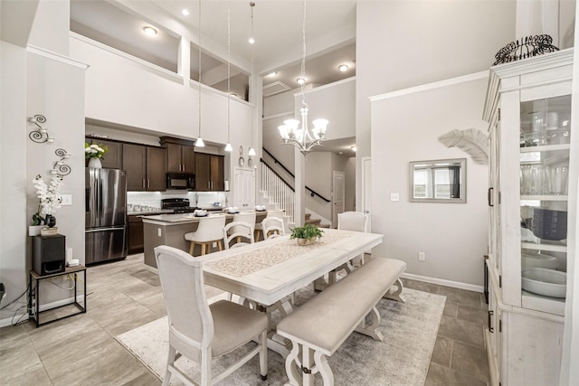 dining space featuring stairs, a high ceiling, a notable chandelier, and baseboards