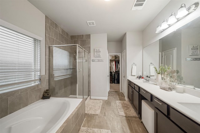 bathroom with a bath, visible vents, a shower stall, and double vanity