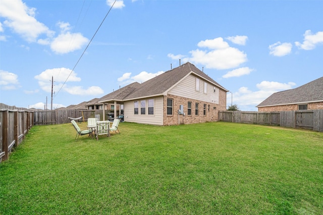 rear view of house featuring brick siding, a fenced backyard, and a lawn