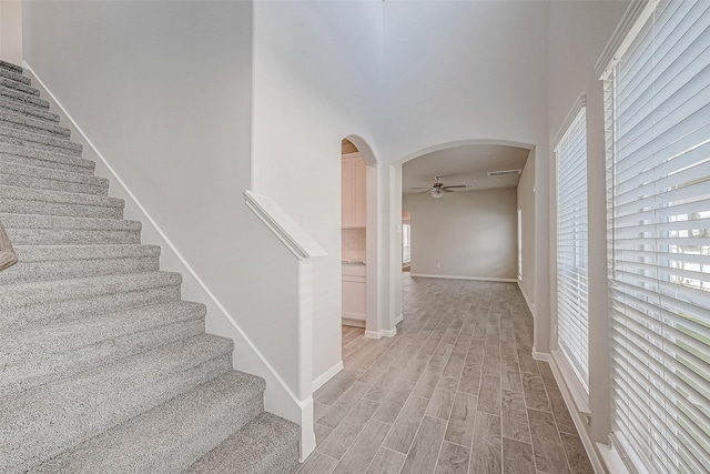 stairway with hardwood / wood-style floors and ceiling fan