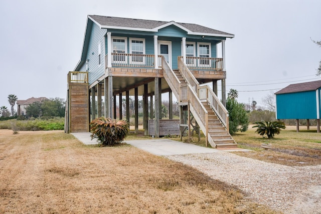 coastal inspired home featuring a porch, a carport, and a front yard