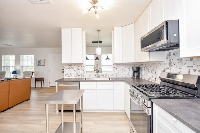 kitchen with pendant lighting, white cabinetry, stainless steel appliances, and sink