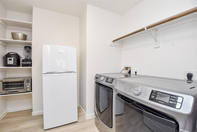 clothes washing area featuring light hardwood / wood-style flooring and washer and dryer