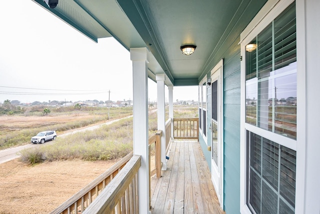 wooden terrace with a rural view and covered porch