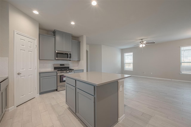 kitchen featuring gray cabinets, stainless steel appliances, a center island, and plenty of natural light