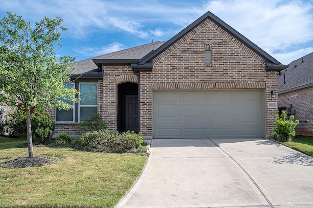 french provincial home featuring a shingled roof, a garage, concrete driveway, brick siding, and a front lawn