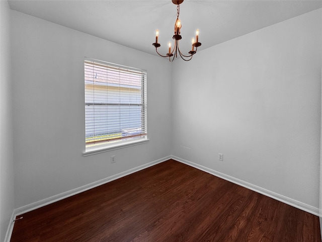 unfurnished room with a notable chandelier, baseboards, and dark wood-style flooring