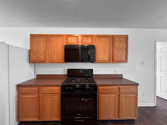 kitchen with dark countertops, brown cabinets, dark wood finished floors, and black appliances