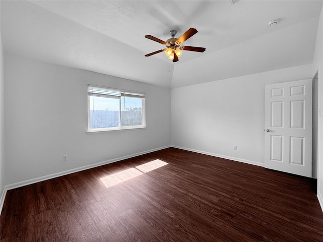 unfurnished room with a ceiling fan, dark wood-style flooring, vaulted ceiling, and baseboards