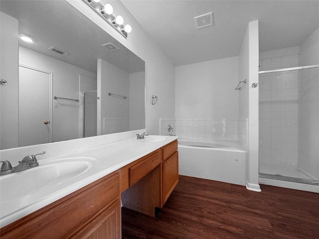 full bath with double vanity, a stall shower, wood finished floors, and visible vents