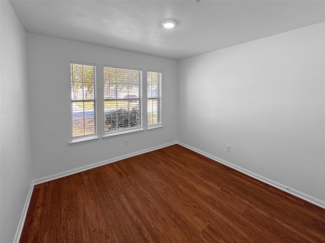 empty room featuring dark wood-type flooring and baseboards