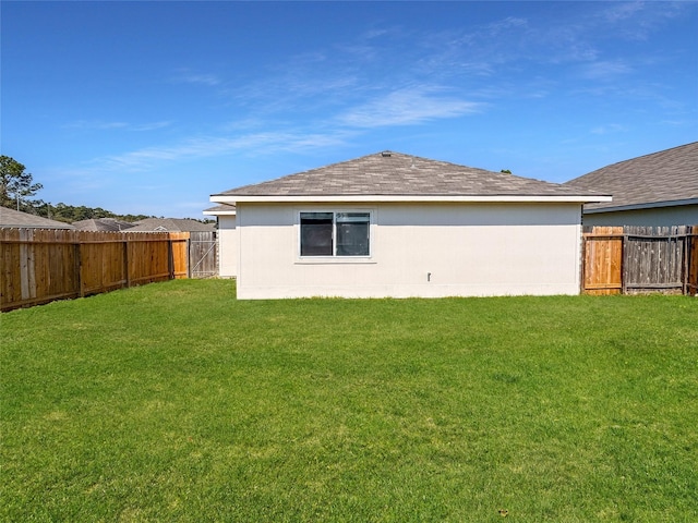 rear view of house featuring a fenced backyard and a yard