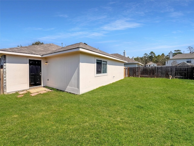 rear view of house with a yard and fence