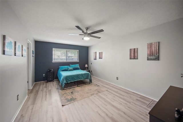 bedroom with ceiling fan, light hardwood / wood-style flooring, and a textured ceiling