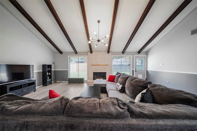 living room with an inviting chandelier, a fireplace, light hardwood / wood-style flooring, and vaulted ceiling with beams