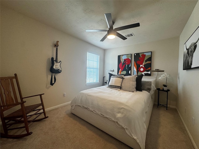 carpeted bedroom with ceiling fan and a textured ceiling