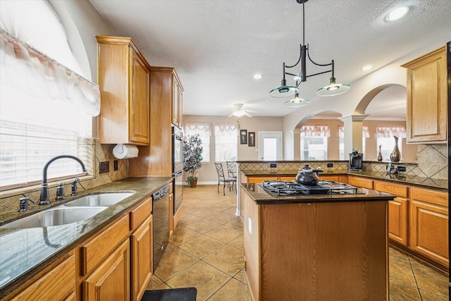 kitchen featuring sink, a center island, dishwasher, decorative light fixtures, and stainless steel gas stovetop