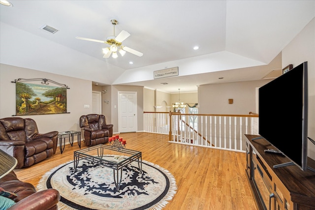 living room featuring ceiling fan with notable chandelier, lofted ceiling, and light hardwood / wood-style flooring