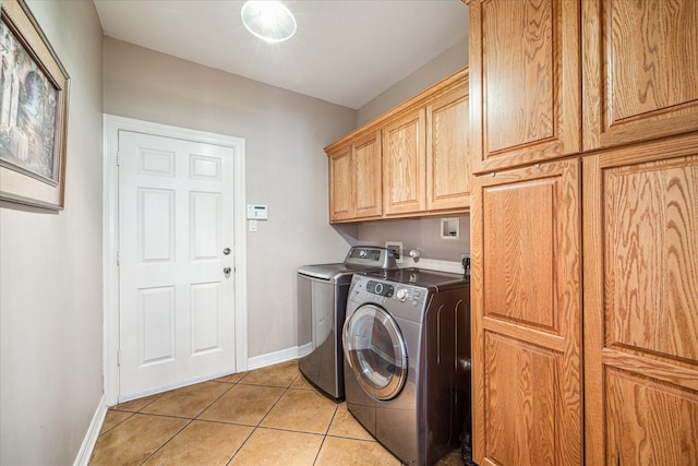 washroom with cabinets, washing machine and dryer, and light tile patterned floors