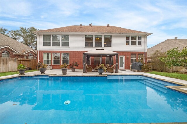 rear view of property featuring an outdoor living space, a gazebo, a patio area, and a fenced in pool